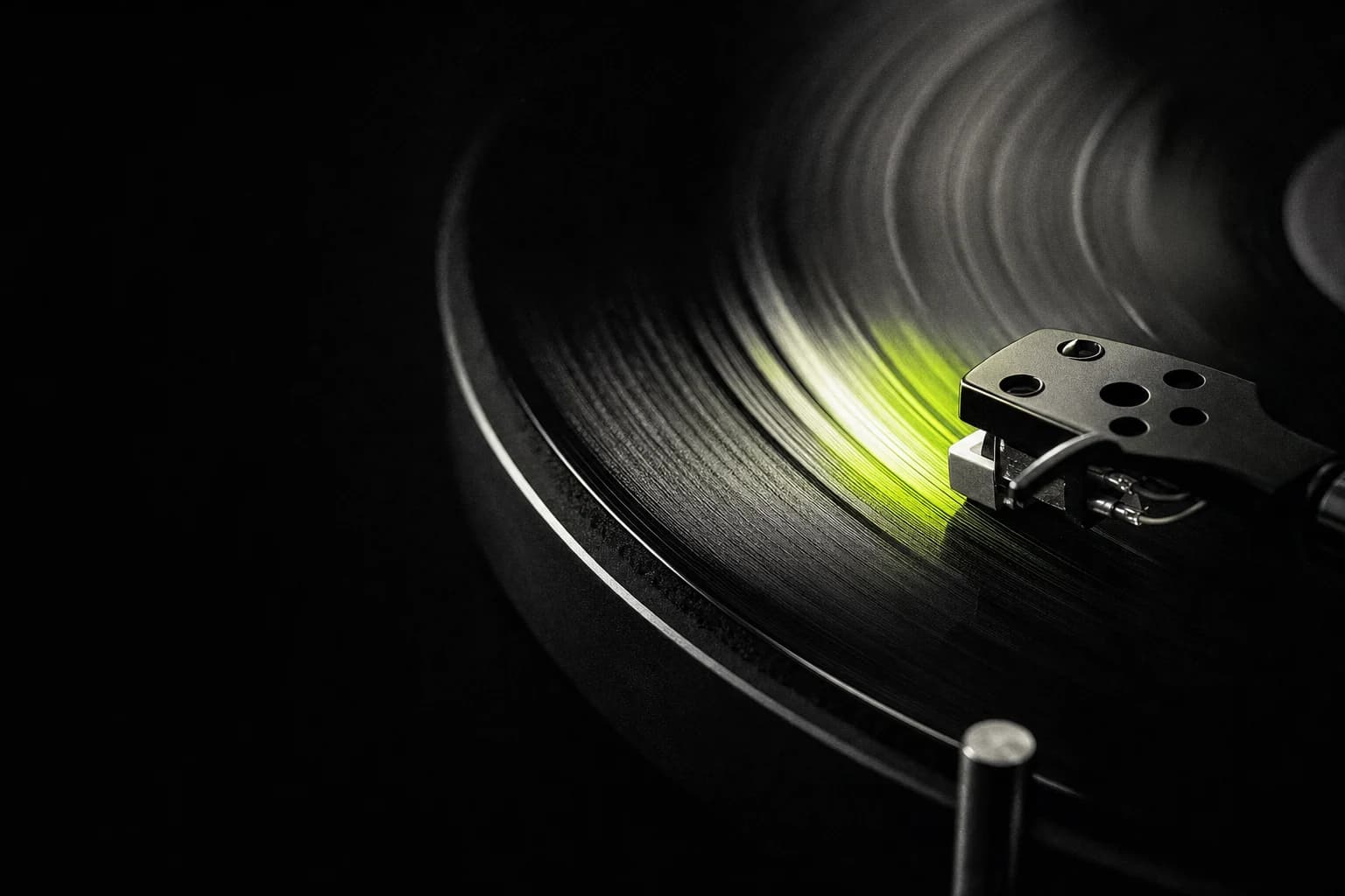Black vinyl record catching a slim line of lime light
